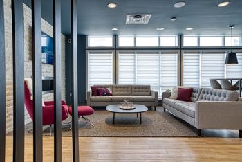 A modern living room with a red chair and a grey couch.